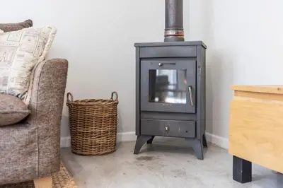 a wood stove in a living room with a couch at Cosy Home in Claremont in Cape Town