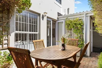 a wooden table and chairs on a patio at Cosy Home in Claremont in Cape Town