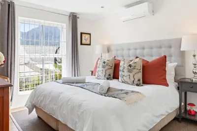 a bedroom with a large bed with orange pillows and a window at Cosy Home in Claremont in Cape Town