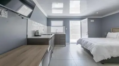 a bedroom with a bed and a sink and a kitchen at Inkantu Apartments & Suites in Cape Town