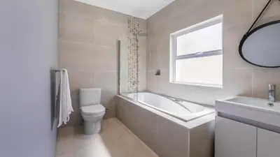 a bathroom with a tub and a toilet and a sink at Inkantu Apartments & Suites in Cape Town