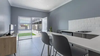 a kitchen with a white counter and chairs in it at Inkantu Apartments & Suites in Cape Town