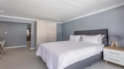 a bedroom with a large white bed and a table at Inkantu Apartments & Suites in Cape Town
