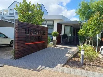 a house with a wooden fence in front of it at The Sandown Blouberg self catering unit in Parklands