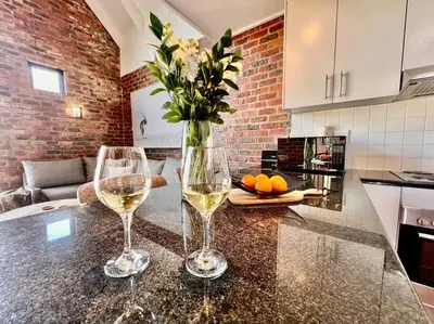 two glasses of wine and a vase with flowers on a counter at Ben's Apartment in Stellenbosch