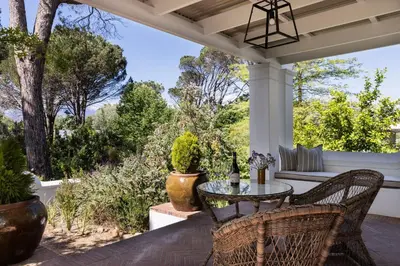 a porch with a table and chairs and trees at Boschendal Farm Estate in Franschhoek