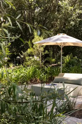 an umbrella sitting in a garden with a bench at Boschendal Farm Estate in Franschhoek
