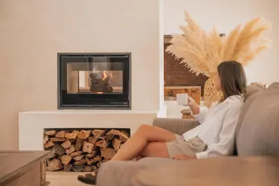a woman sitting on a couch in a living room with a fireplace at Menuha Hermanus in Hermanus
