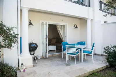 a patio with blue chairs and a table at Maison Des Huguenots Le Roux in Franschhoek