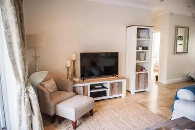 a living room with a television and a chair at Maison Des Huguenots Le Roux in Franschhoek