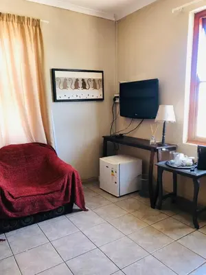 a living room with a television and a table with a desk at Bergsig Casa Guest House in Cape Town