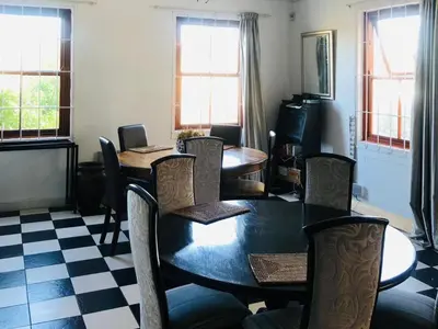 a dining room with a table and chairs and a checkerboard floor at Bergsig Casa Guest House in Cape Town