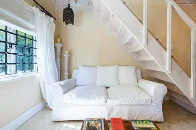 a white couch in a living room with stairs at Devon Castle Orchard Cottage in Stellenbosch