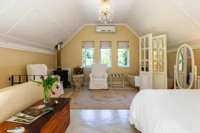a large bedroom with a bed and a bathroom at Devon Castle Orchard Cottage in Stellenbosch