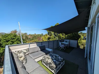 a patio with a couch and a table on a balcony at 116m² SeaView TopLuxury Apart, Bay & Mountain View in Somerset West