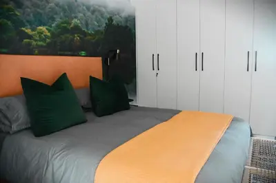 a bedroom with a large bed with green pillows at Designer Luxe Stellies Studio in Stellenbosch