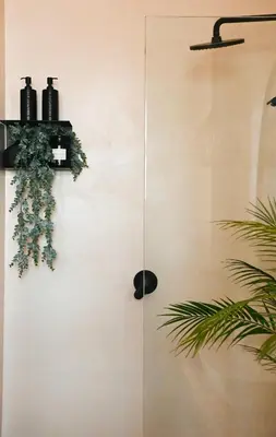 a shower with a cross on the wall next to a plant at Designer Luxe Stellies Studio in Stellenbosch