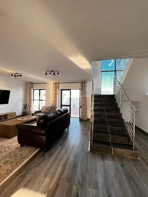 a living room with a black couch and a staircase at 2nd on Strand in Cape Town