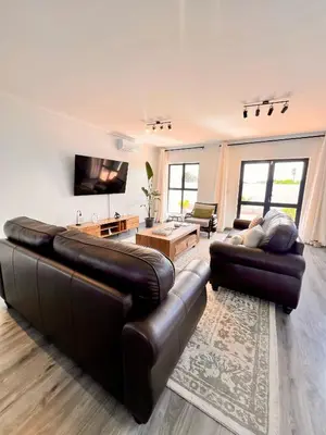 a living room with two leather couches and a television at 2nd on Strand in Cape Town