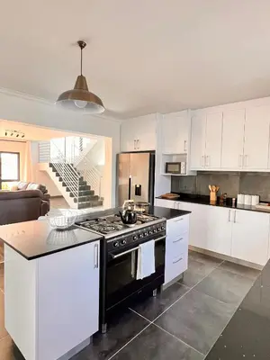 a kitchen with white cabinets and a stove top oven at 2nd on Strand in Cape Town