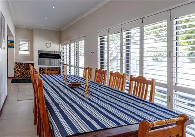 a dining room with a table and chairs and windows at Seabreeze in Hermanus