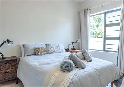 a bedroom with a bed with pillows and a window at Seabreeze in Hermanus