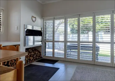 a living room with large windows with blinds at Seabreeze in Hermanus