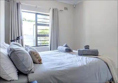 a bedroom with a bed with pillows and a window at Seabreeze in Hermanus