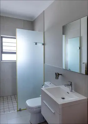 a bathroom with a toilet and a sink and a mirror at Seabreeze in Hermanus