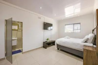 a white bedroom with a bed and a sink at One bedroom apartment. in Cape Town