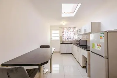 a large kitchen with a table and a refrigerator at One bedroom apartment. in Cape Town