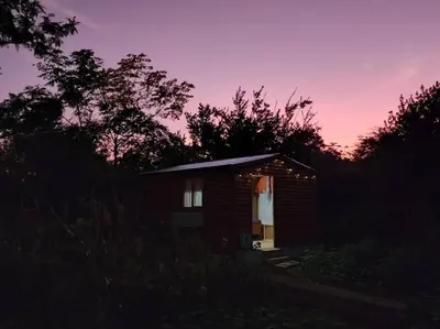 a small cabin with a lit up window at sunset at Gypsy Mama in Greyton in Greyton