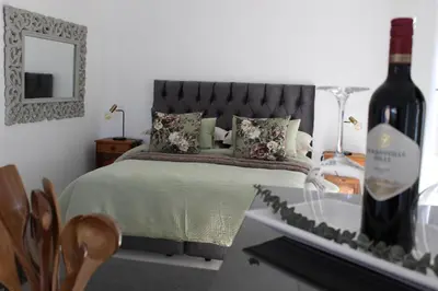 a bedroom with a bed with a bottle of wine at Nivenia Beach House in Bettyʼs Bay