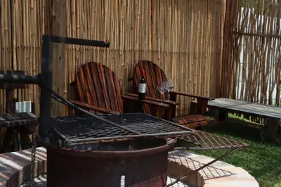 two chairs with a bottle of wine and a bench at Nivenia Beach House in Bettyʼs Bay