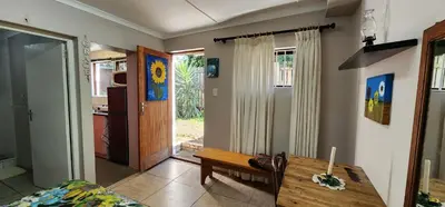 a living room with a wooden table and a kitchen at Sundance in Central Greyton in Greyton
