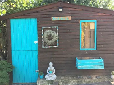 a smallshed with a blue door and a statue in front at PONDOKKIE in Greyton