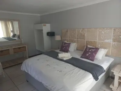 a bedroom with a large bed with purple pillows at Crystal Villa Guesthouse in Cape Town