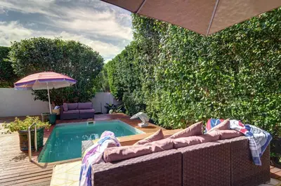 a patio with a couch and an umbrella next to a pool at Dieu Donne in Hermanus