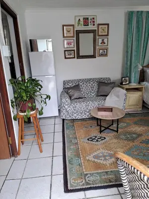 a living room with a couch and a table at Watercolour Cottage in Hermanus