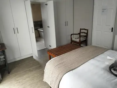 a bedroom with a bed and a chair and a bathroom at Hermanus 13 on 2nd Guest Rooms in Hermanus