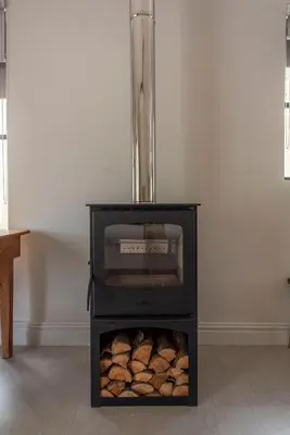 a black oven with a pile of logs in a room at Franschhoek Colours in Franschhoek