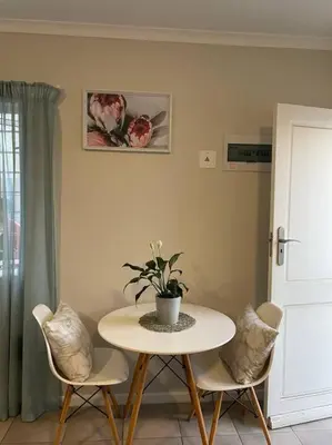 a table and two chairs with a potted plant on it at Modest Home in Cape Town in Cape Town