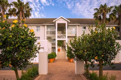 a large white building with trees in front of it at Seaside Serenity: Tranquil Oceanview Retreat in Hermanus