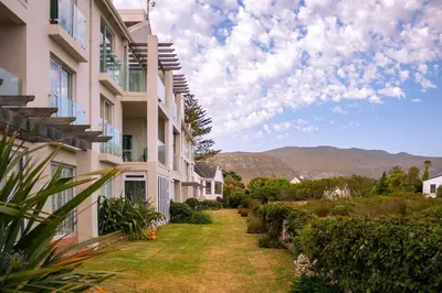 a path between two buildings with mountains in the background at Seaside Serenity: Tranquil Oceanview Retreat in Hermanus