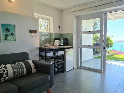 a living room with a couch and a sliding glass door at 'BoStrand' - Private and Central, only 2 min walk to beach - sleeps 2 in Gordonʼs Bay