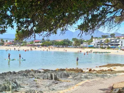 a group of people swimming in the water on a beach at 'BoStrand' - Private and Central, only 2 min walk to beach - sleeps 2 in Gordonʼs Bay