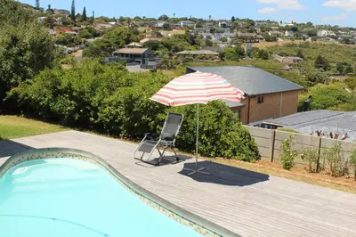 a patio with an umbrella and a chair next to a pool at Hidden gem on Eksteen in Cape Town