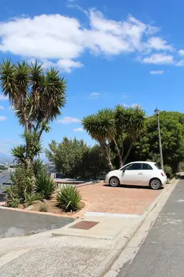 a white car parked in a parking lot with palm trees at Hidden gem on Eksteen in Cape Town