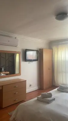 a bedroom with a bed and a dresser and a mirror at The Other House - Cape Town in Cape Town