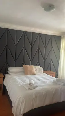 a bedroom with a large white bed with a gray headboard at The Other House - Cape Town in Cape Town